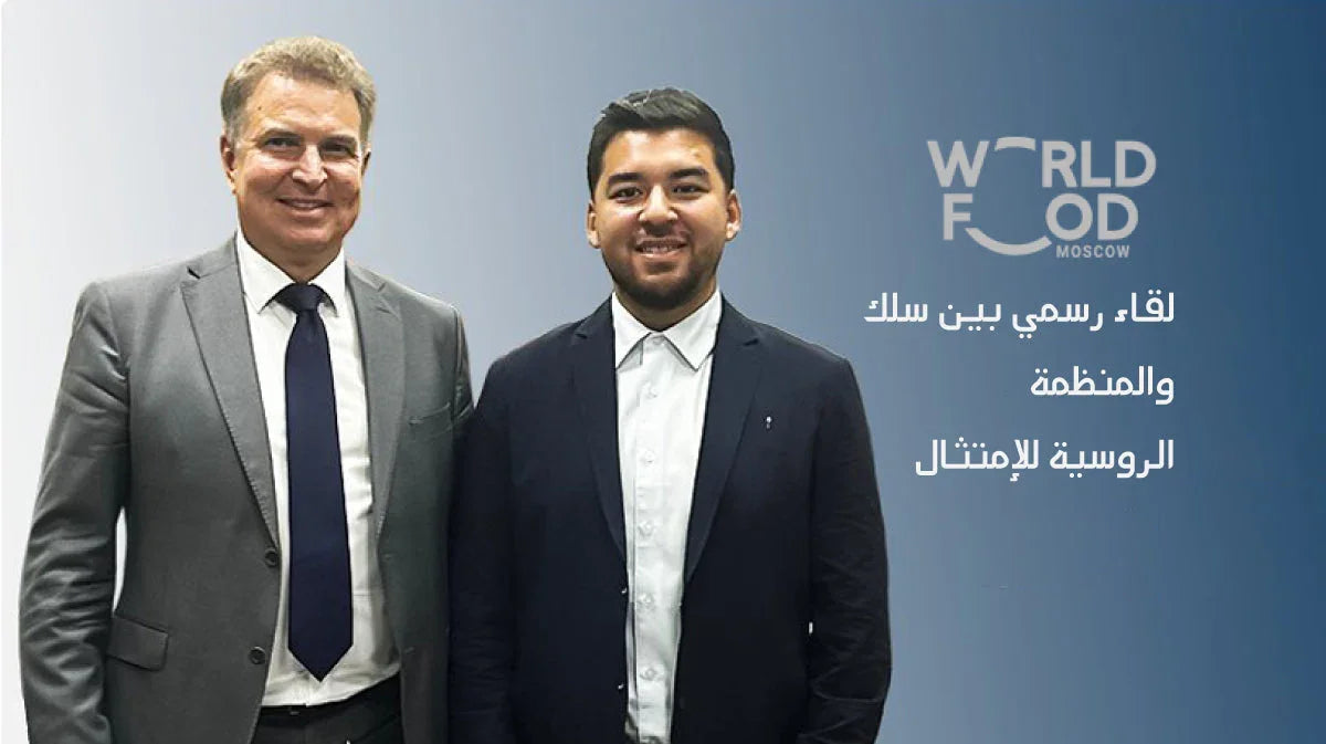 Two businessmen in suits standing together beside the World Food Moscow logo and Arabic text.