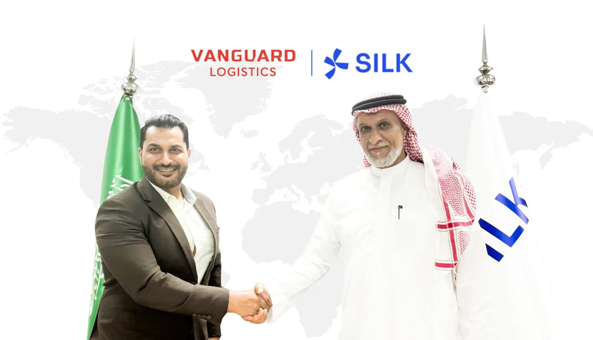 Two executives shaking hands under Vanguard Logistics and Silk logos with flags and a world map.