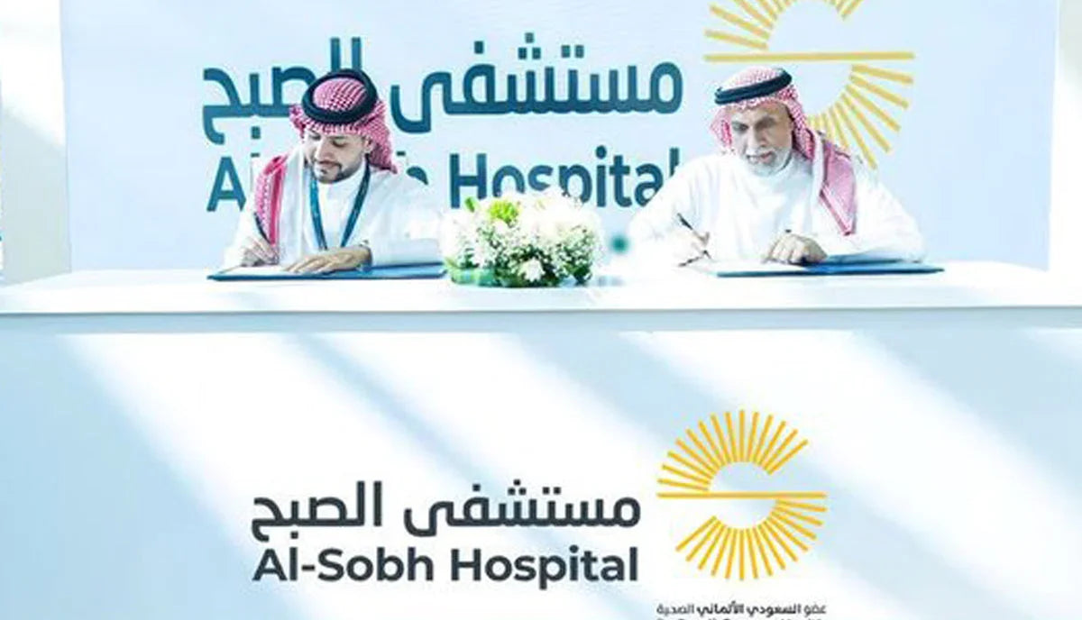 Two men in traditional Saudi attire signing a partnership agreement at Al-Sobh Hospital.
