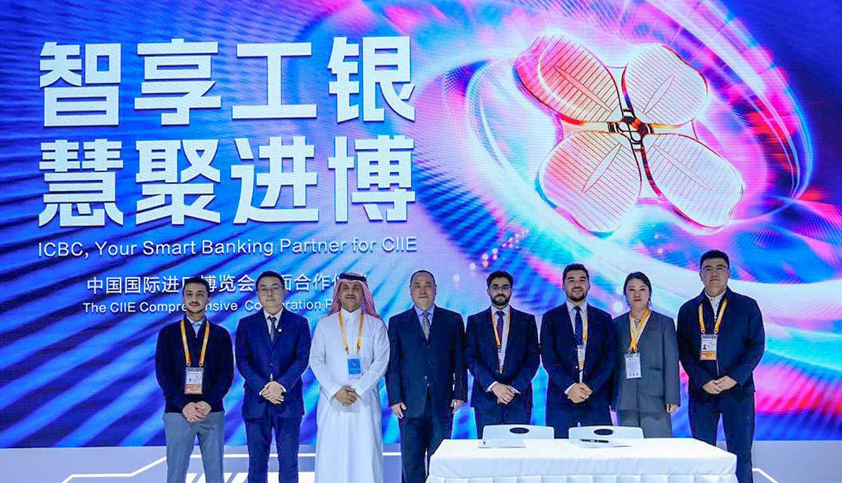 Group of business professionals posing in front of an ICBC smart banking display at CIIE.