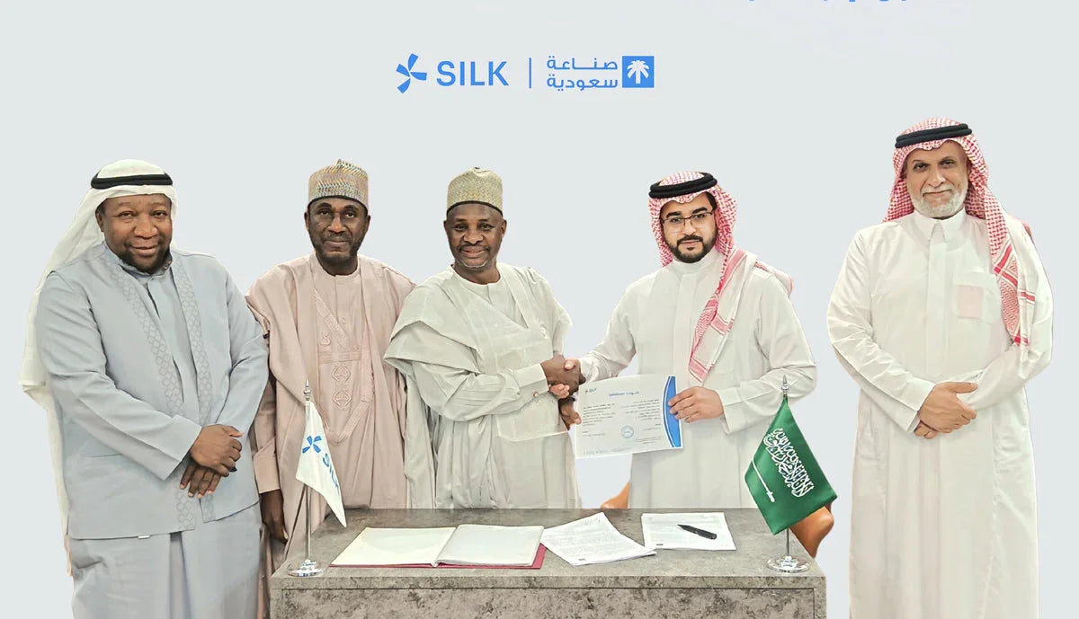 Five businessmen in traditional attire shaking hands and holding a document in front of a SILK logo.