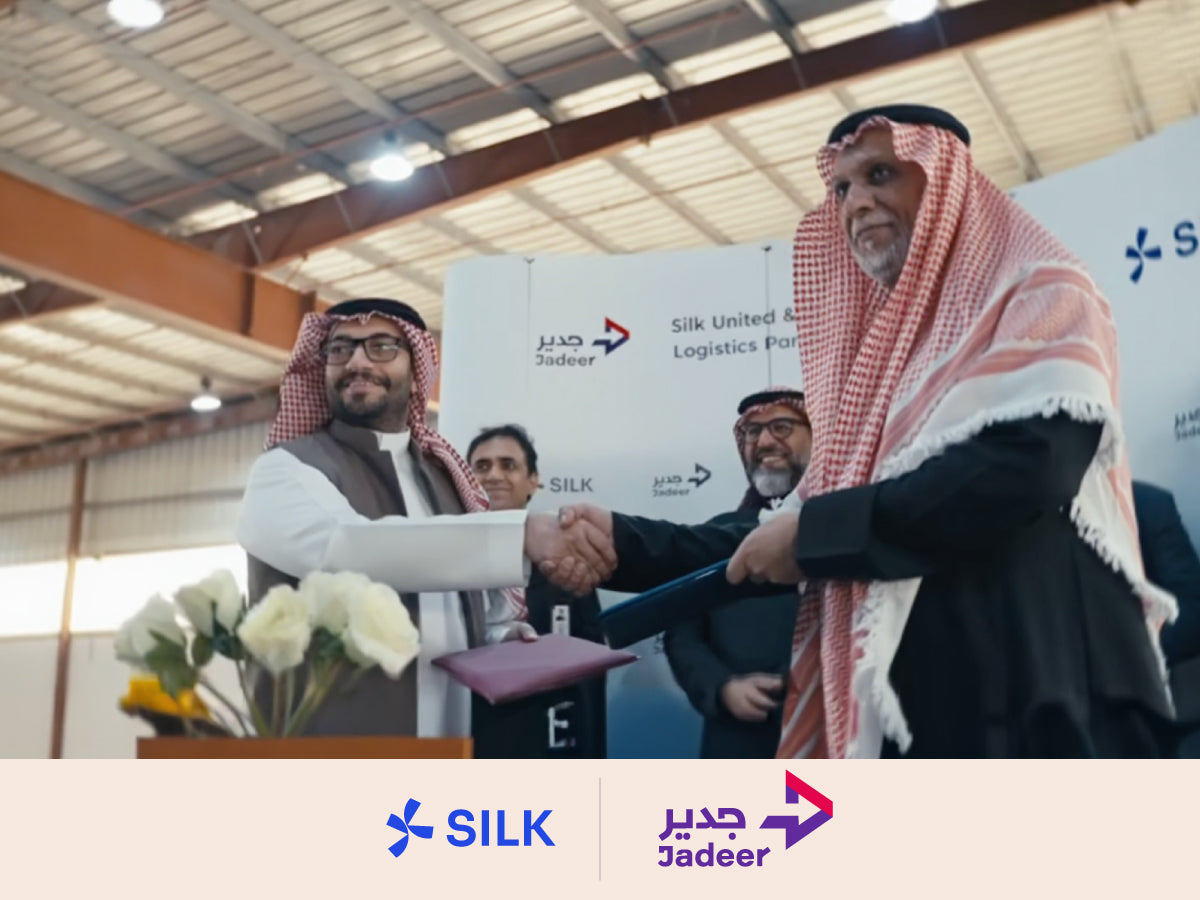 Executives from Silk United and Jadeer shaking hands during a partnership agreement signing.