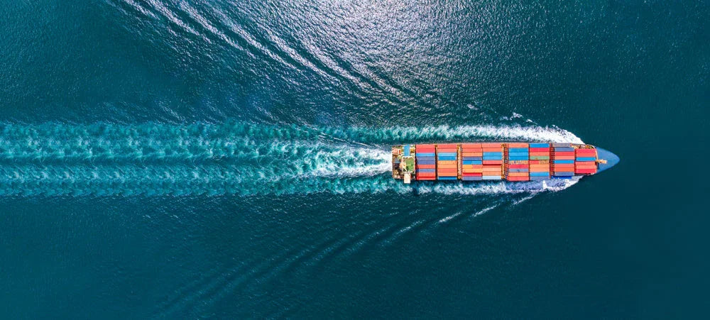 Aerial view of a cargo ship transporting colorful containers across a blue ocean