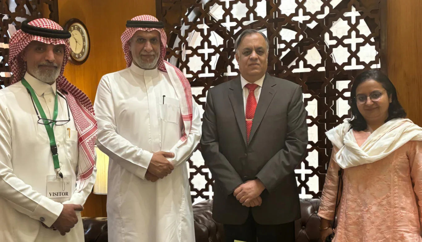 Four business professionals standing together in front of an ornate wooden screen.